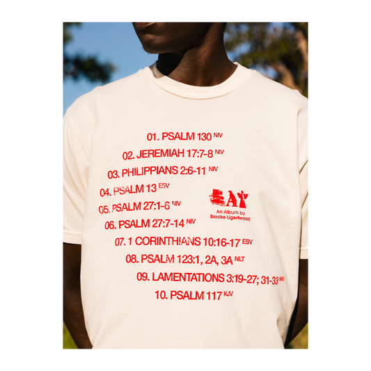 Person wearing a white t-shirt with red text and an Eat logo, outdoors.