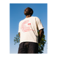 Person wearing a white t-shirt with red text and an Eat logo, outdoors.