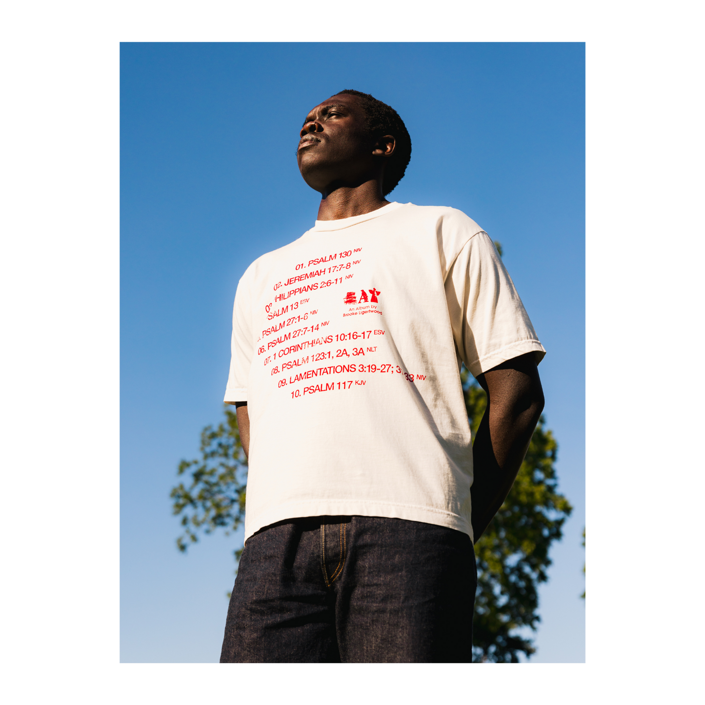Person wearing a white t-shirt with red text and an Eat logo, outdoors.