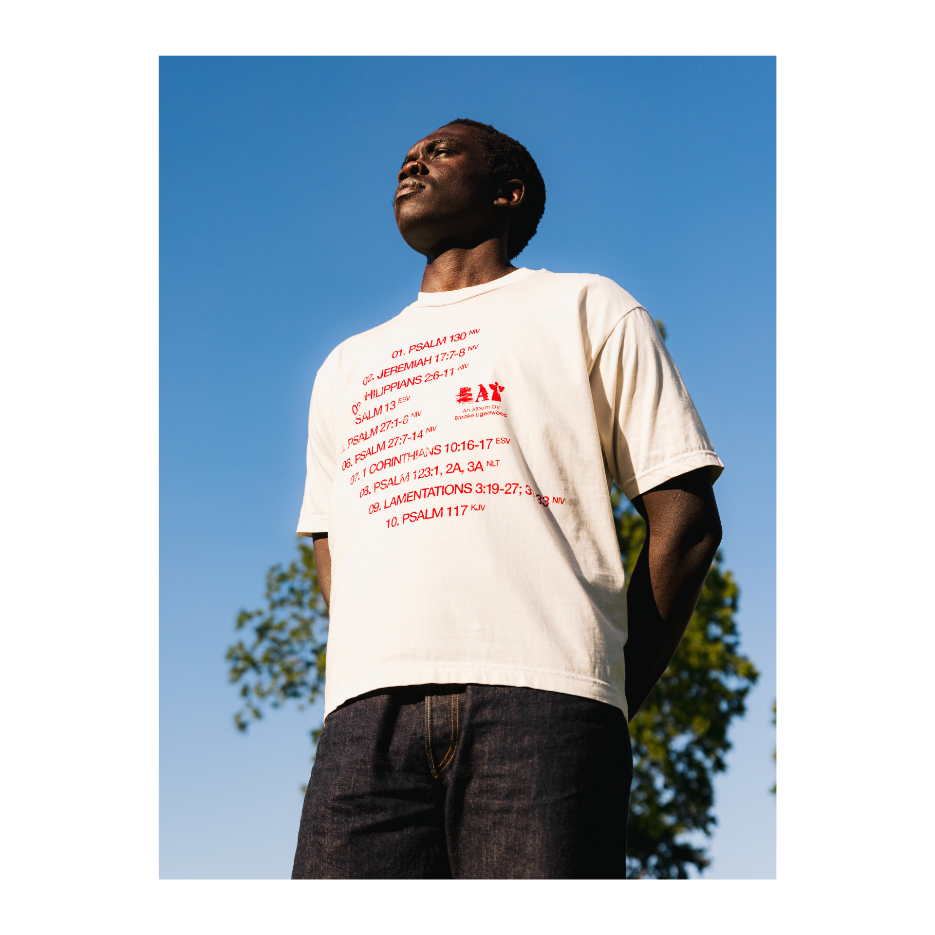 Person wearing a white t-shirt with red text and an Eat logo, outdoors.