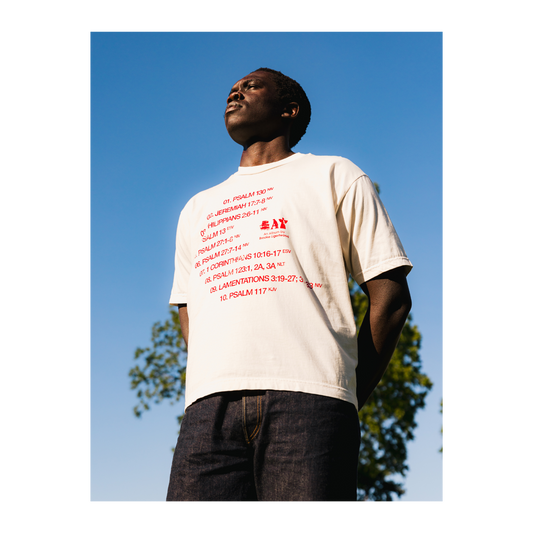 Person wearing a white t-shirt with red text and an Eat logo, outdoors.