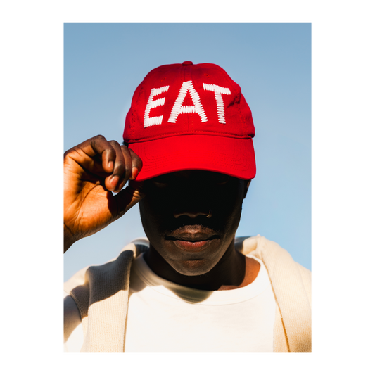 Person wearing a red cap or hat with 'EAT' text against a clear blue sky
