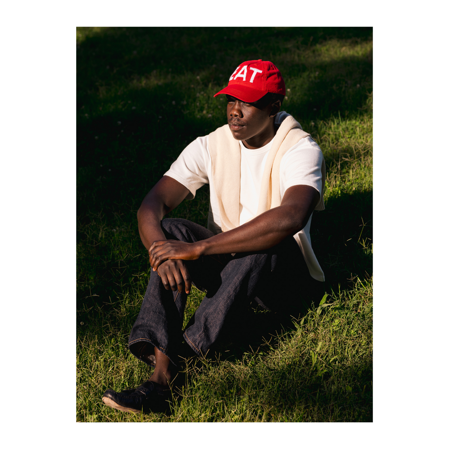 Person wearing a red cap or hat with text, sitting on grass