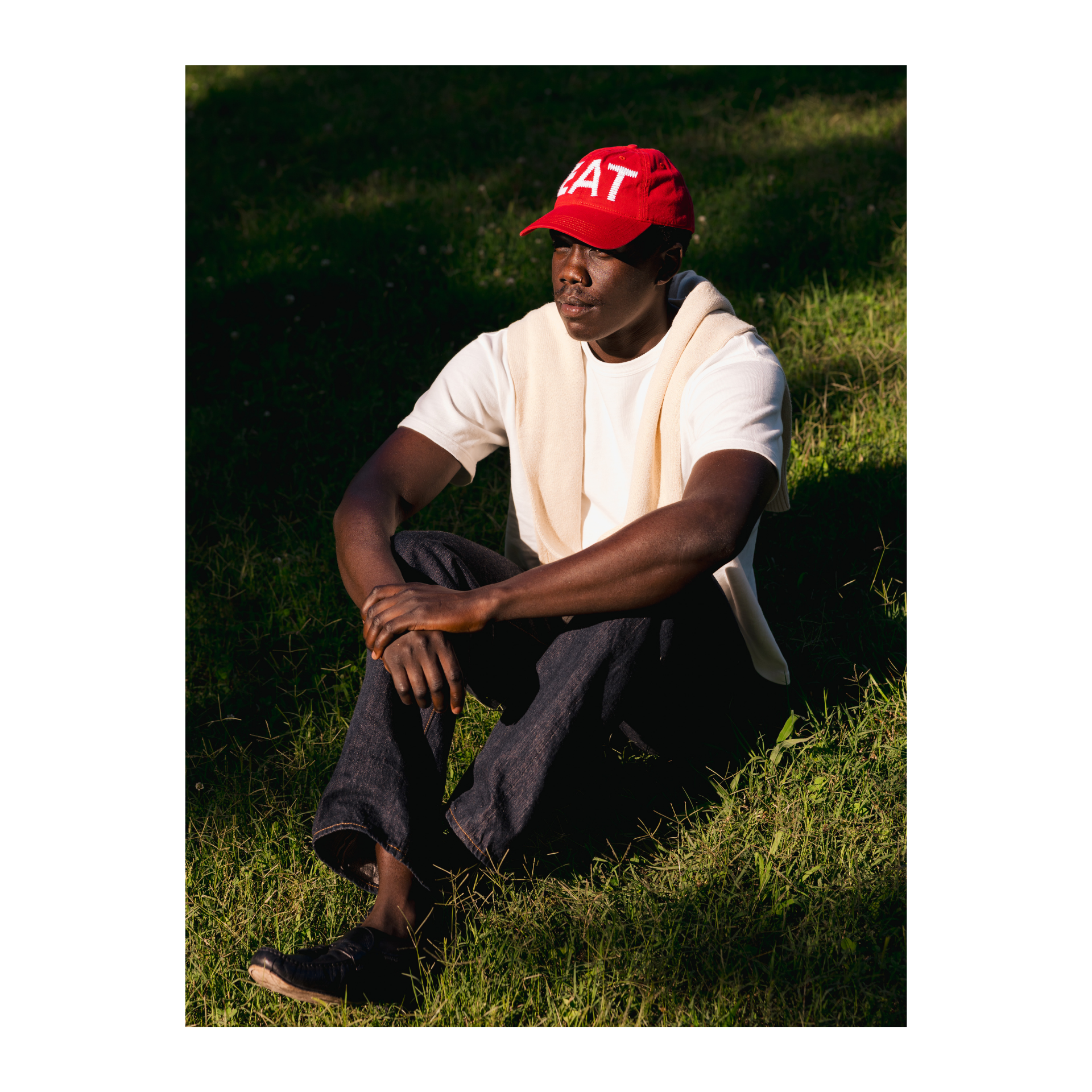 Person wearing a red cap or hat with text, sitting on grass